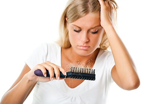Девушка держит расческу с выпавшими волосами