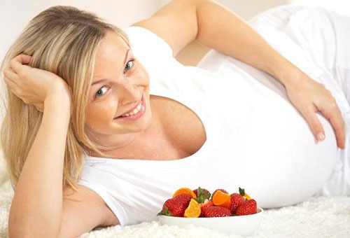 Беременная женщина с тарелкой фруктов и ягод
